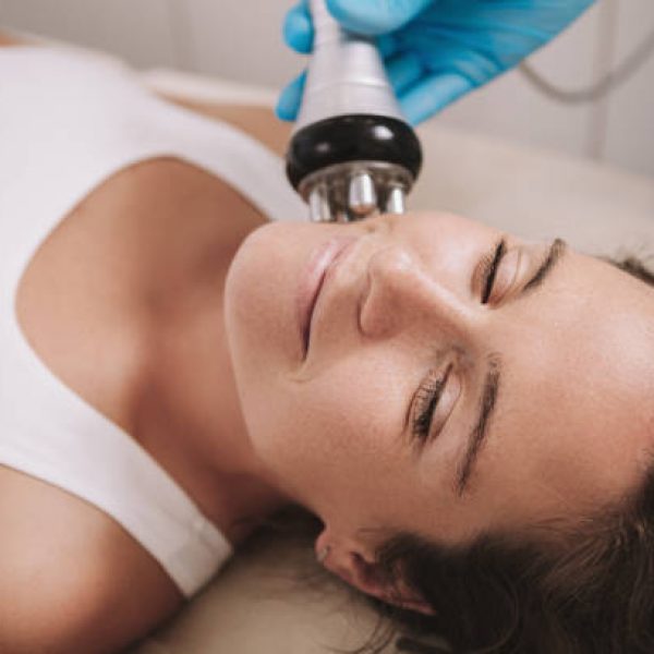 Close up of a cheerful mature woman enjoying facial rf-lifting procedure at beauty salon. Attractive female relaxing during rf-lifting treatment by cosmetologist